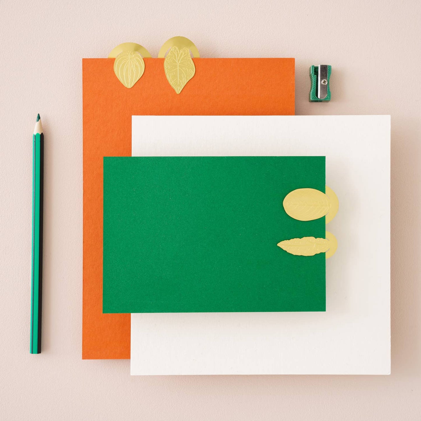 Three colorful notebooks with leaf decorations on a beige background