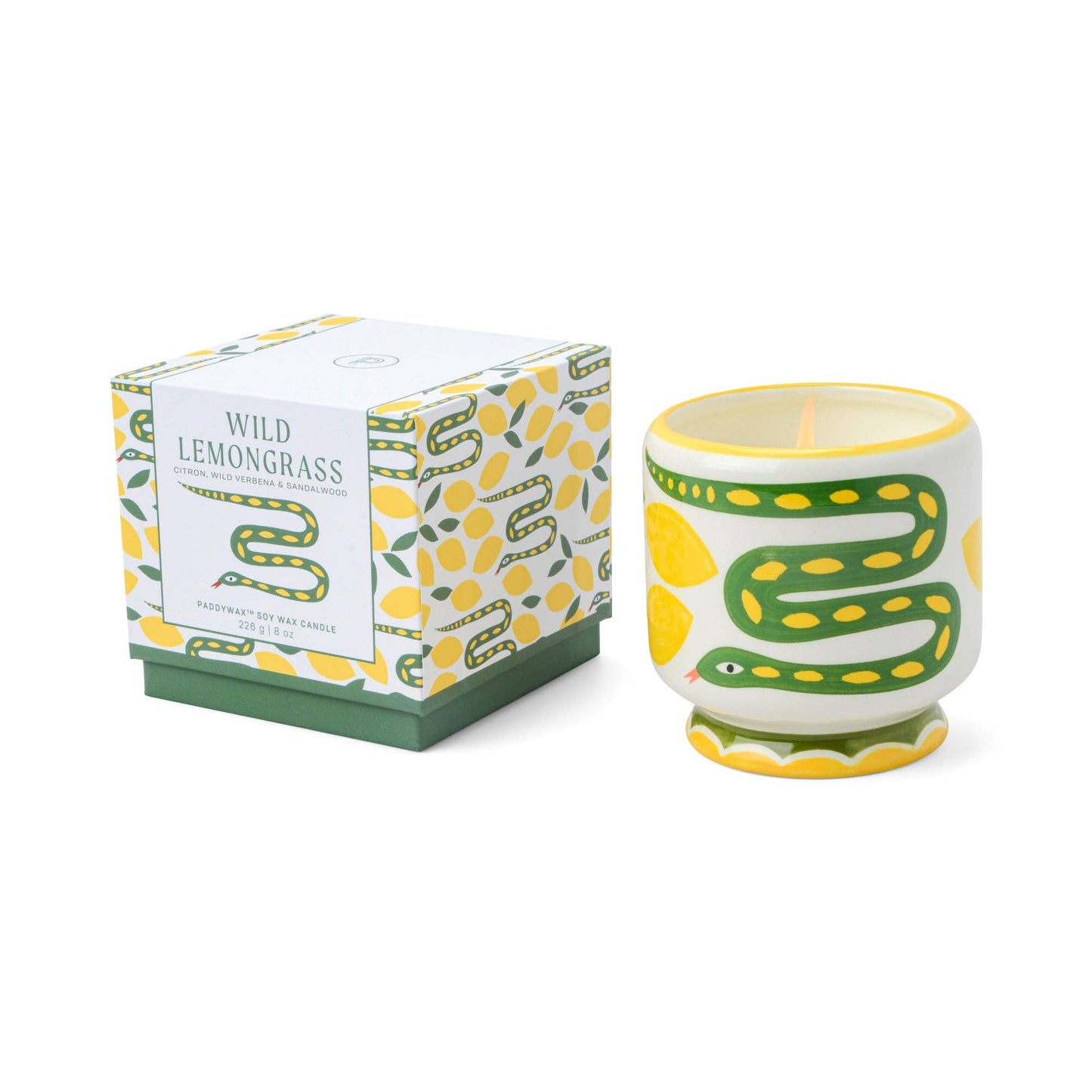 Ceramic candle with green and yellow design next to its packaging on a white background