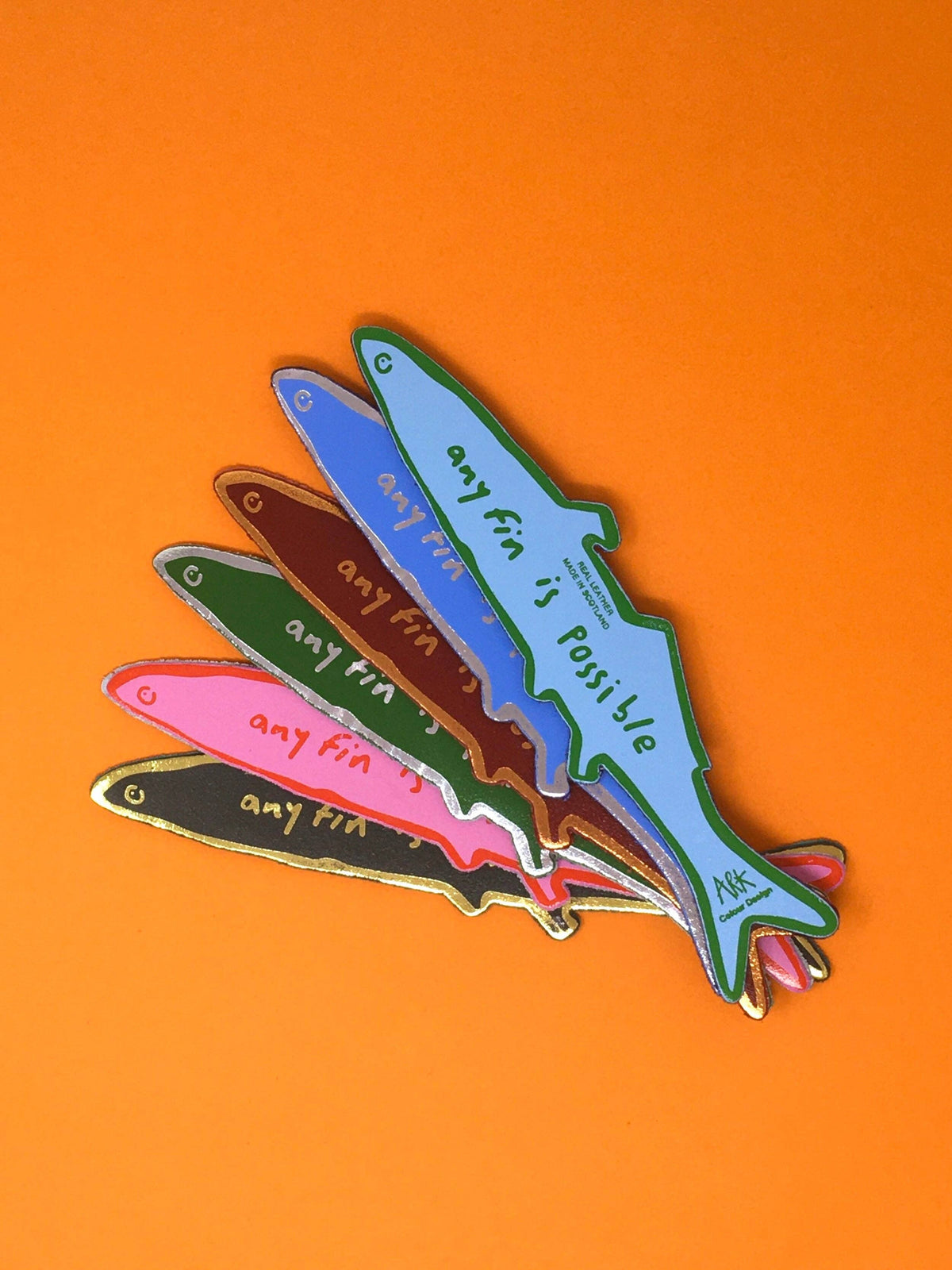 Colorful fish-shaped pins with 'any fin is possible' text on an orange background