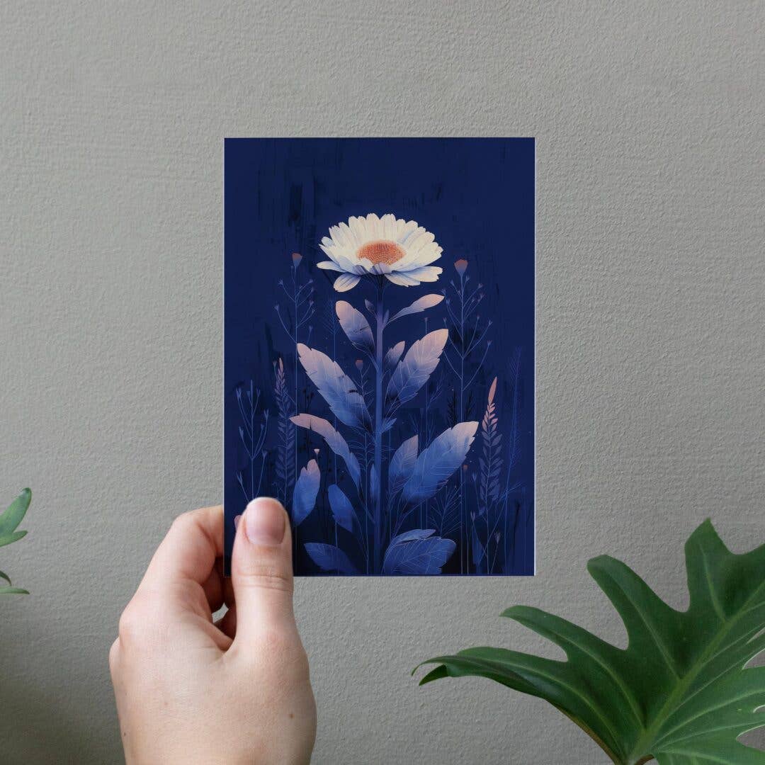 Hand holding a card with a floral design against a gray wall.