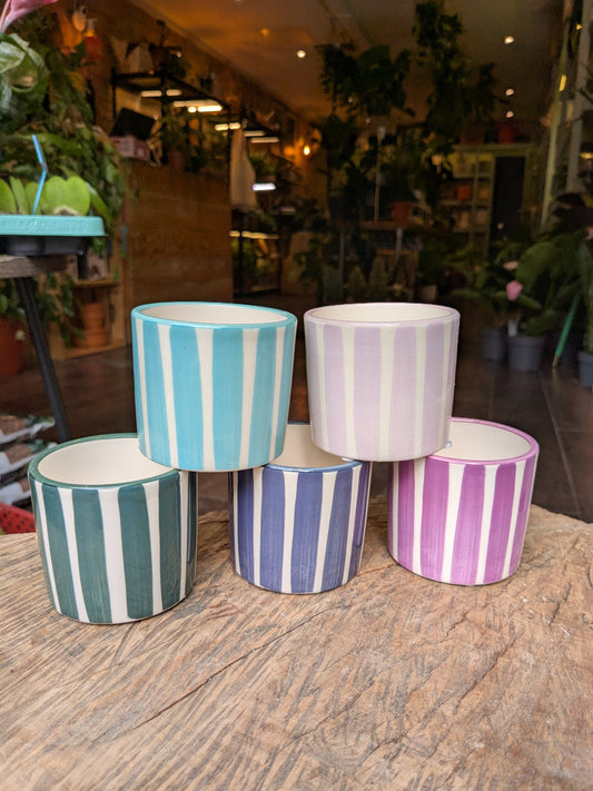 Set of striped ceramic pots on a wooden surface with a blurred indoor background