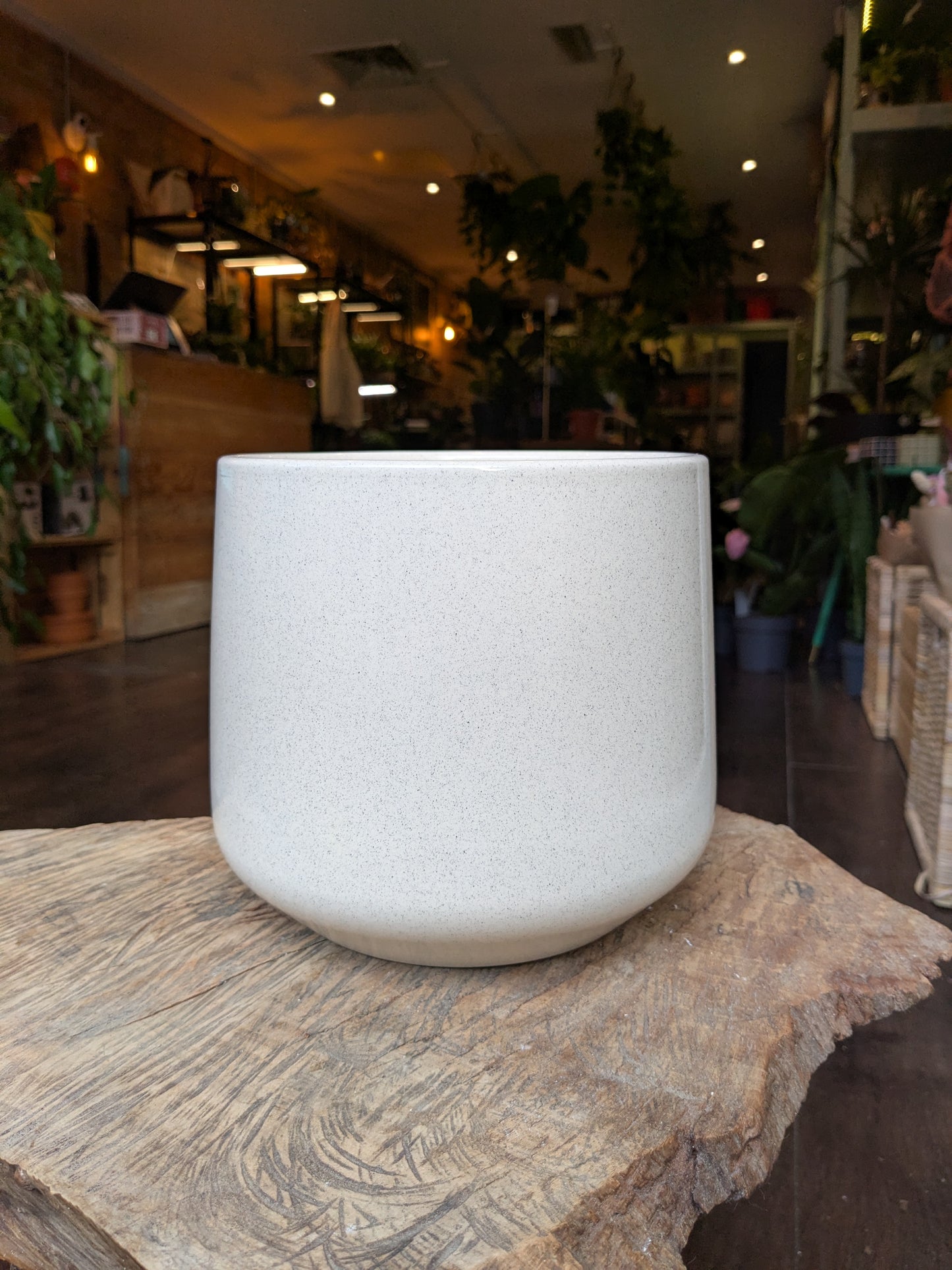 White textured vase on a wooden surface with a blurred indoor setting