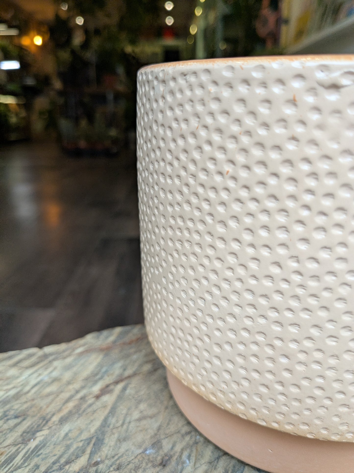 Textured ceramic pot on a surface with a blurred background