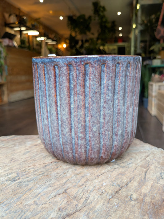Textured ceramic pot on a stone surface with a blurred indoor background