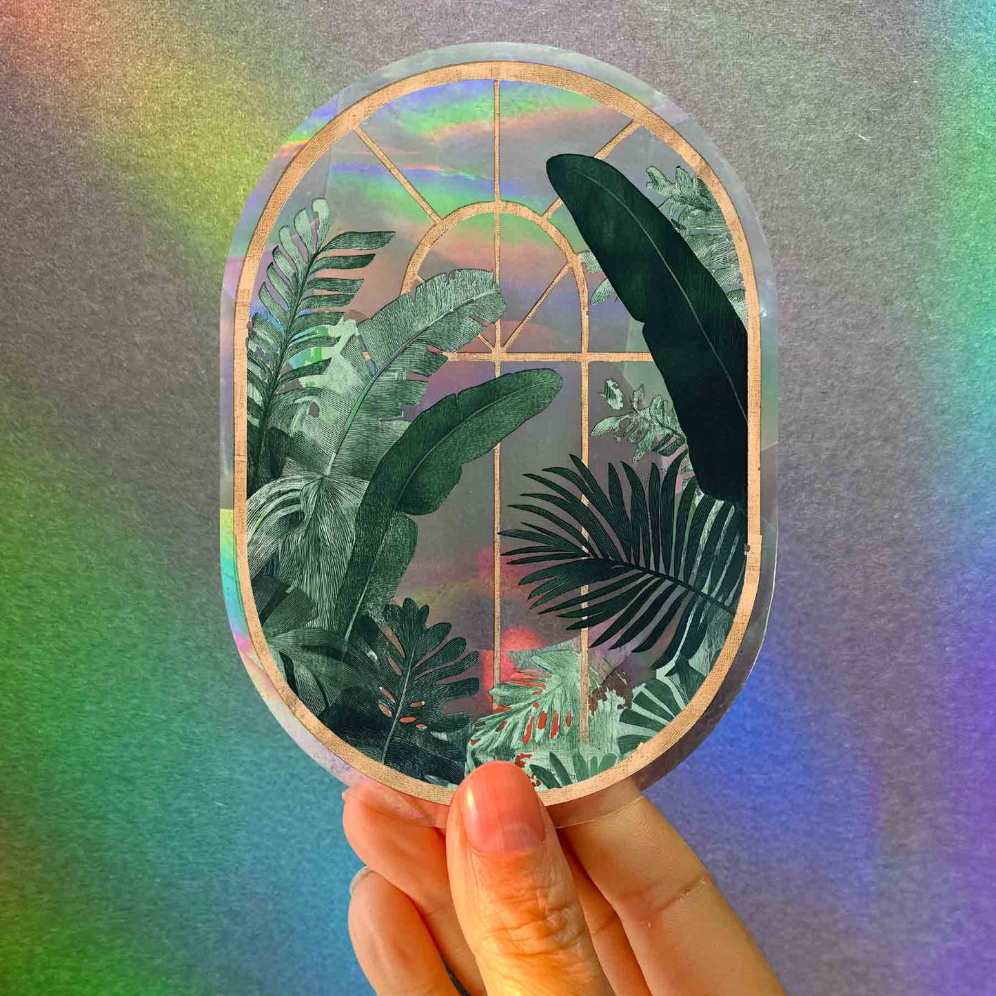 Holographic sticker with tropical leaf design held against a colorful gradient background