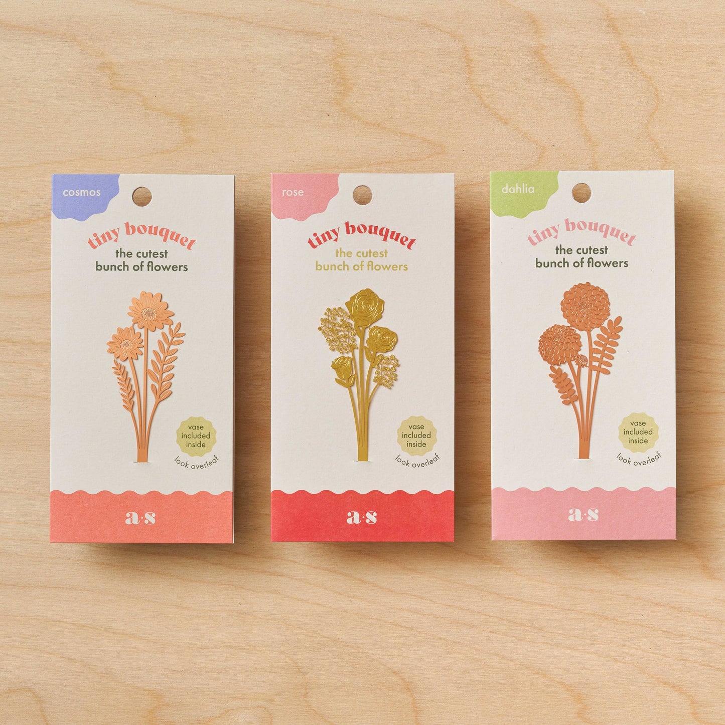 Three packages of 'tiny bouquet' on a wooden surface