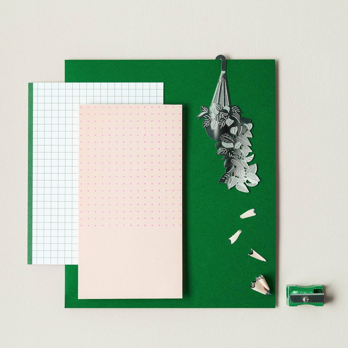 Green notepad with various paper sheets and stationery items on a light background