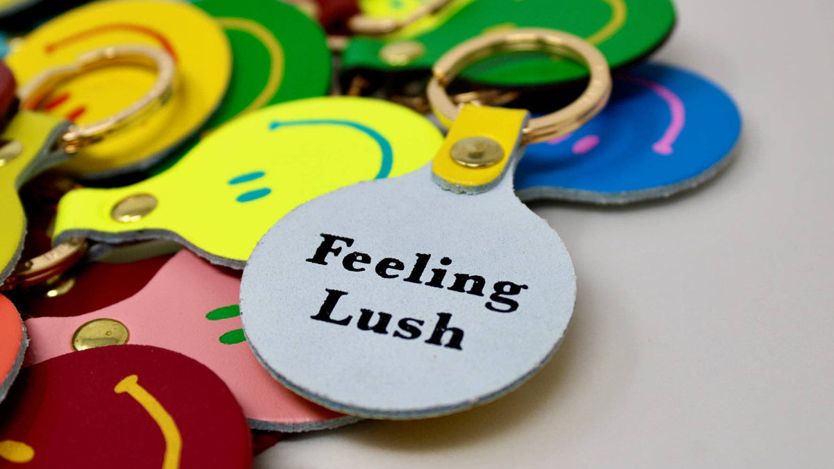 Colorful keychains with a tag labeled 'Feeling Lush' on a light background