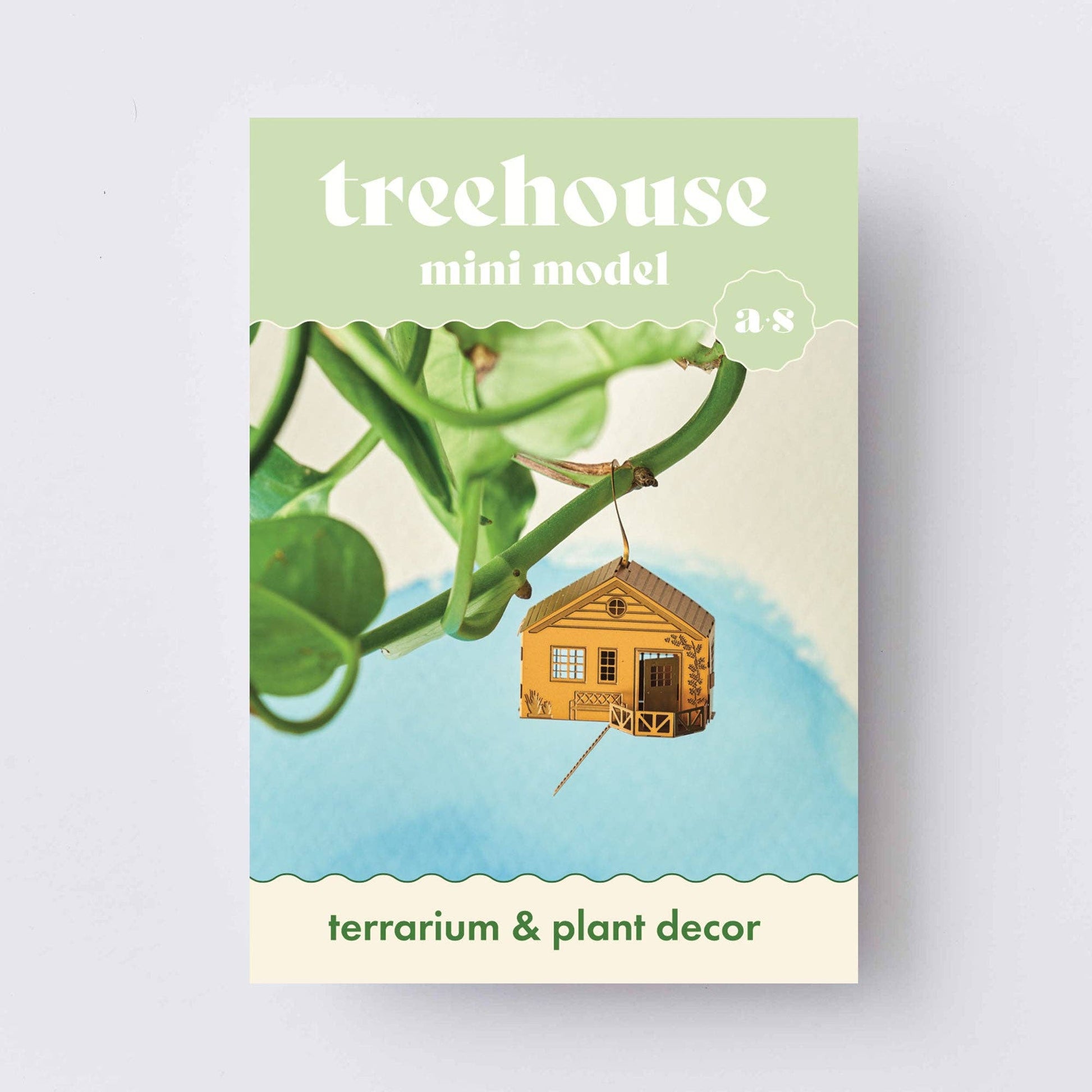 Product packaging for a mini treehouse terrarium decor with greenery on a light gray background