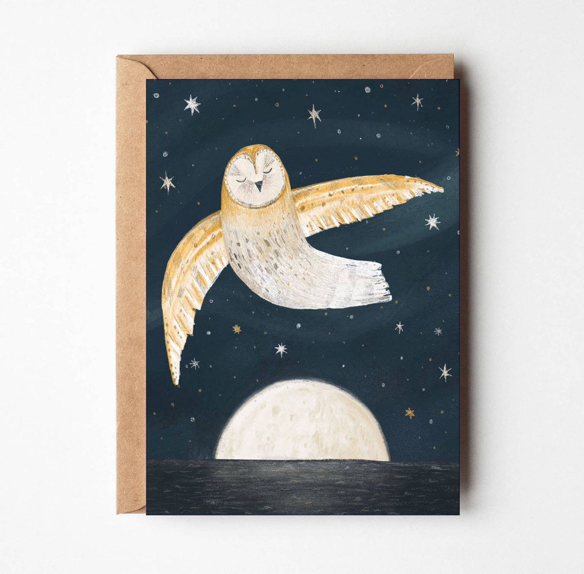 A square greeting card with a kraft envelope, featuring an illustration of a barn owl flying across a dark starry night sky above a large moon.