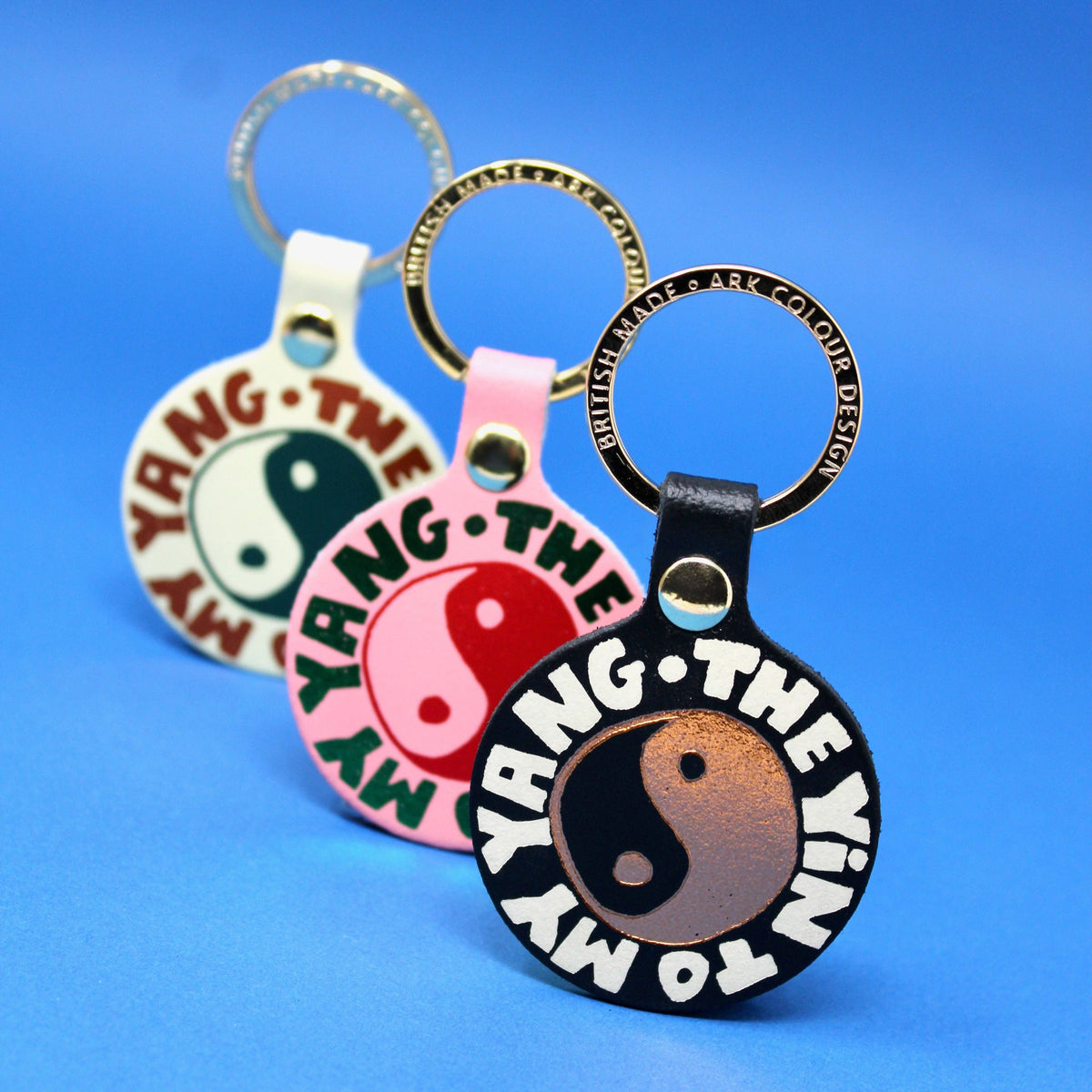 Three keychains with yin and yang symbols on a blue background