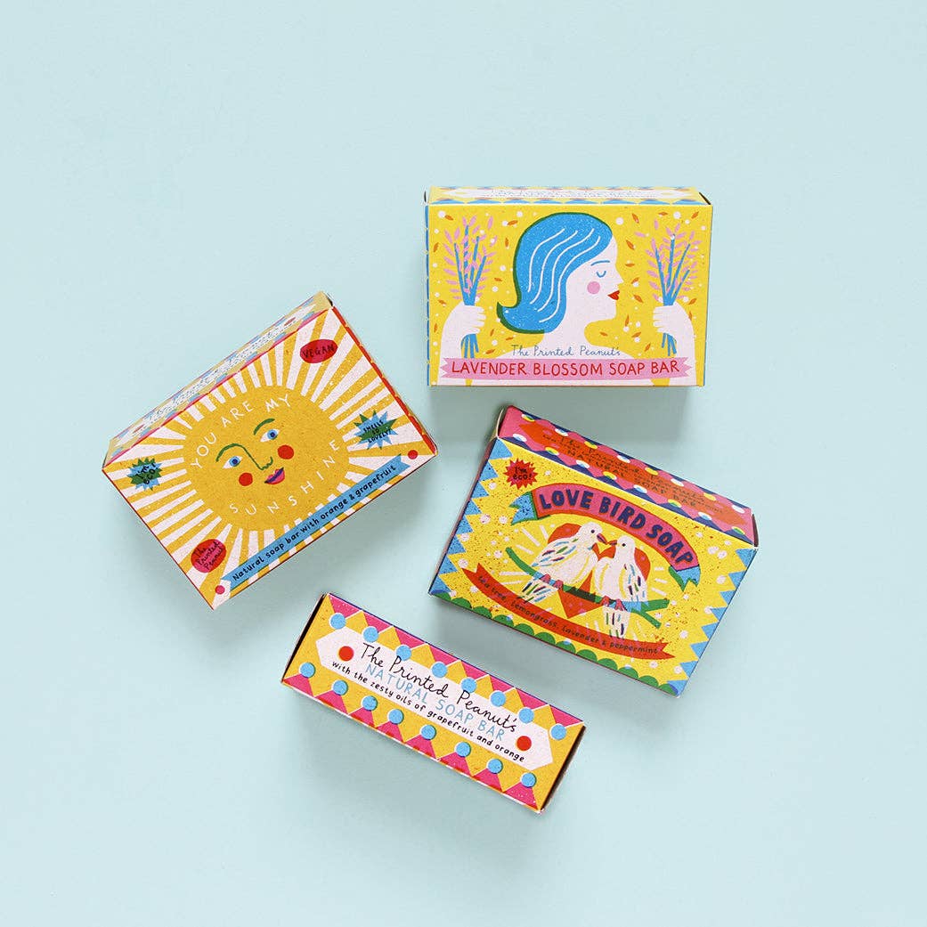 Four colorful soap boxes with artistic designs on a light blue background