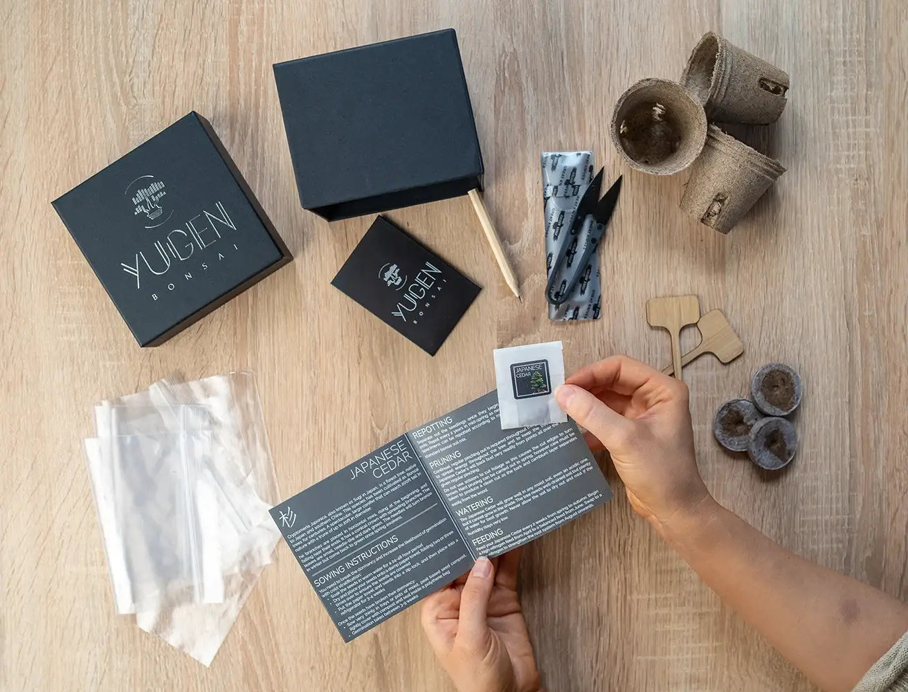 Person holding a YUEN product manual on a wooden surface with various items including boxes and packaging.