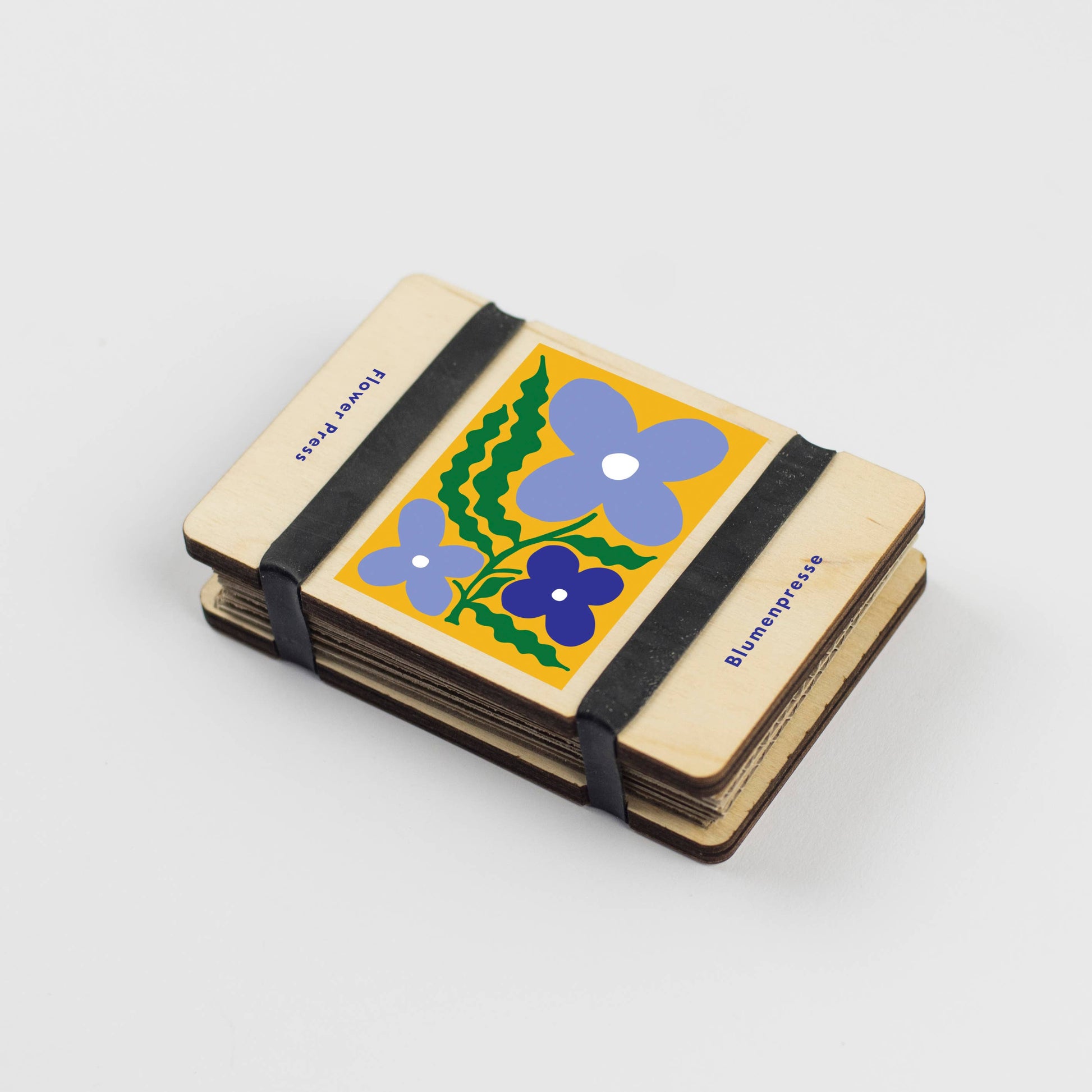 Small notebook with floral design and black strap on a white background