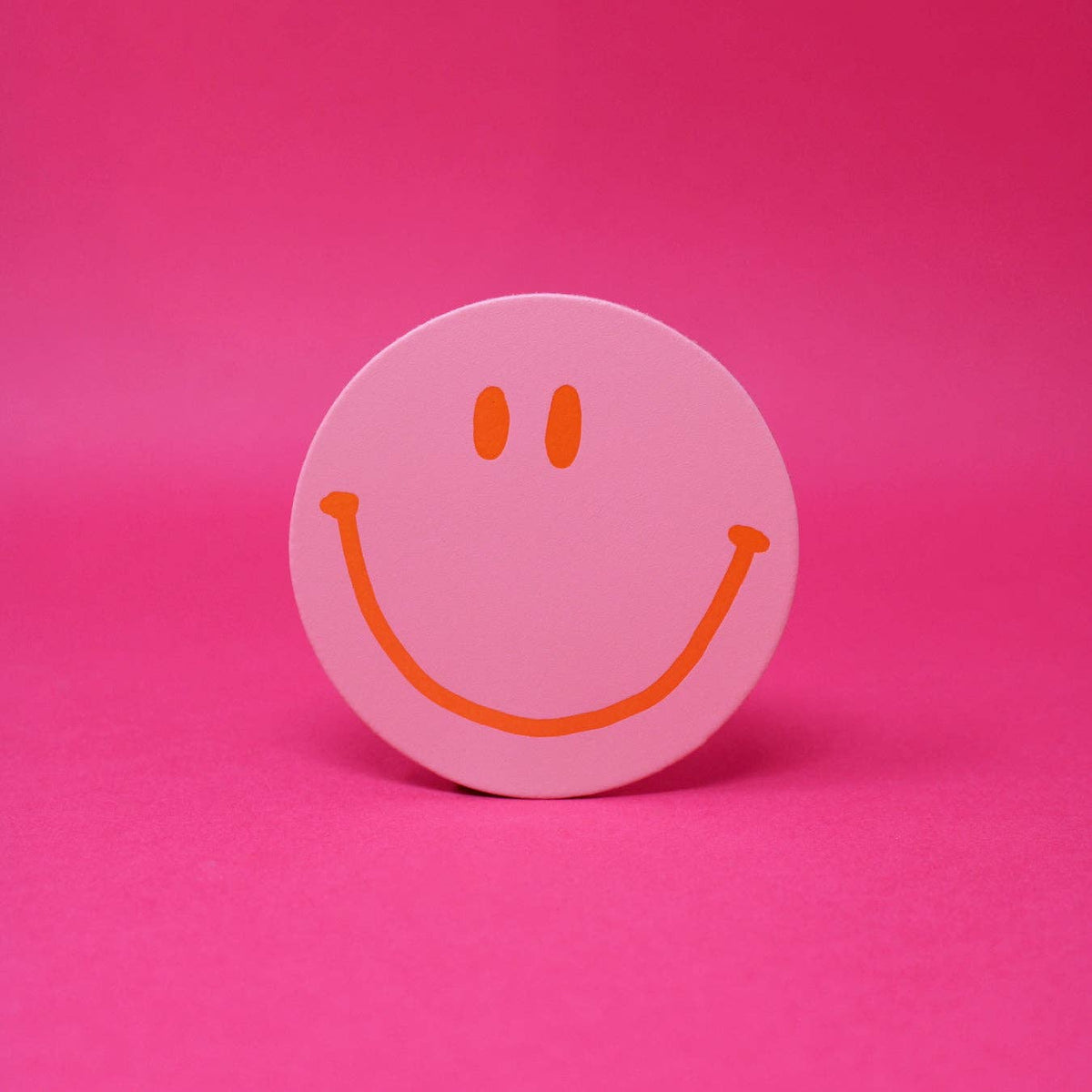 Pink smiley face sticker on a pink background