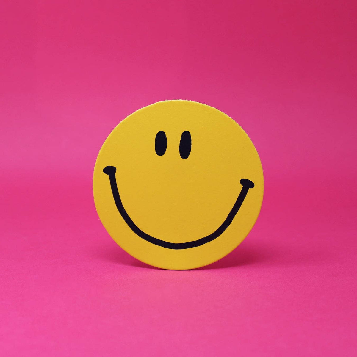Yellow smiley face sticker on a pink background