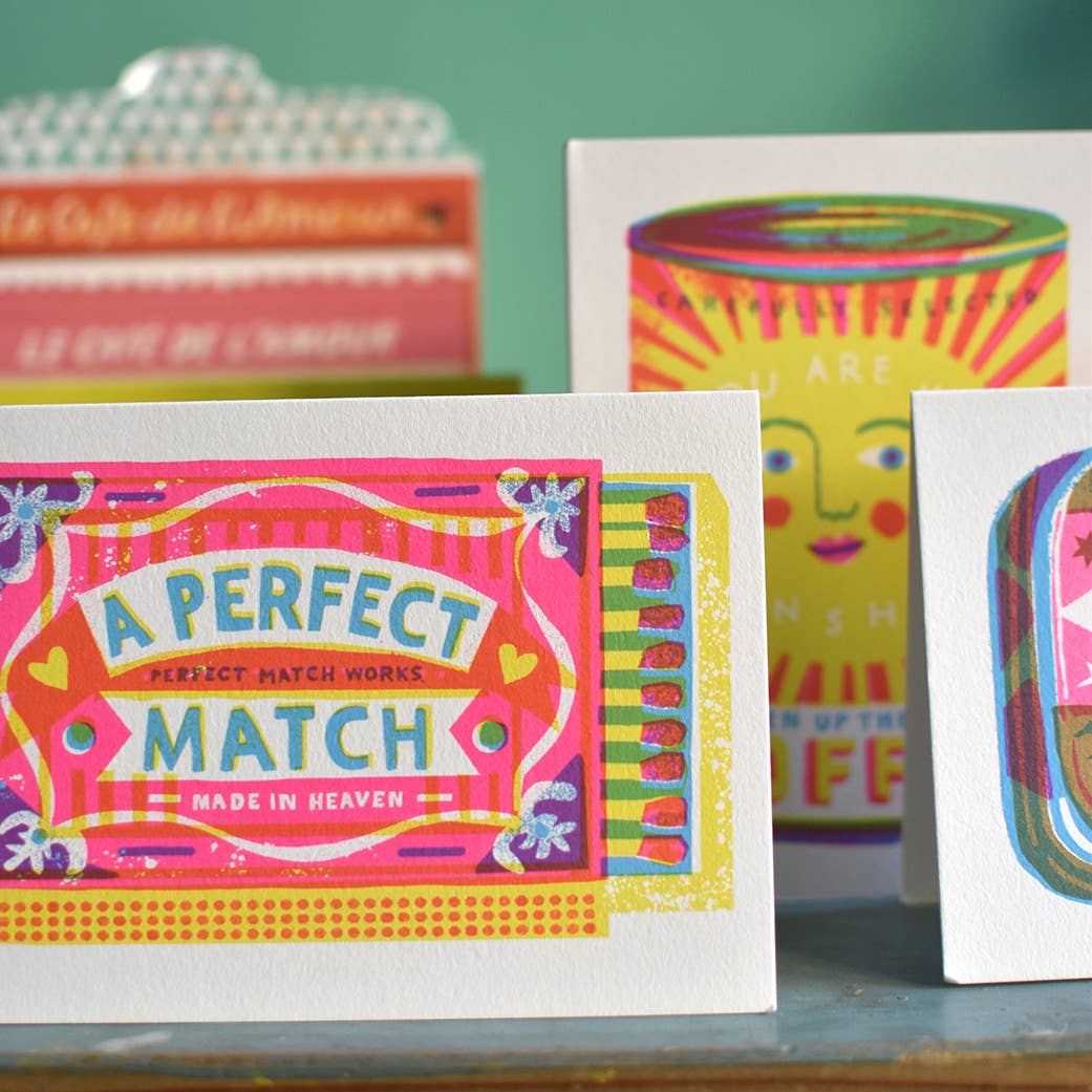 Colorful greeting cards with playful designs on a wooden surface.