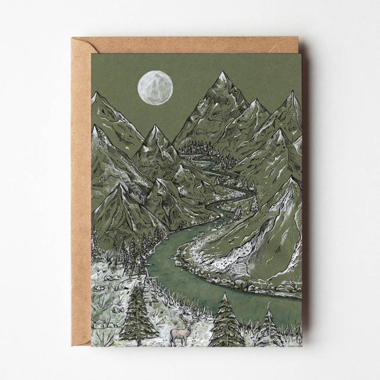 A square art print or card featuring a mountain landscape illustration with a winding river, trees, and a full moon, shown with a kraft envelope against a light neutral background.