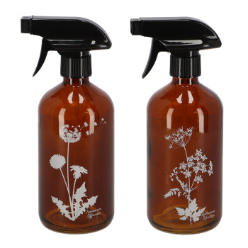 Two brown glass spray bottles with black nozzles and white floral etchings on a white background.