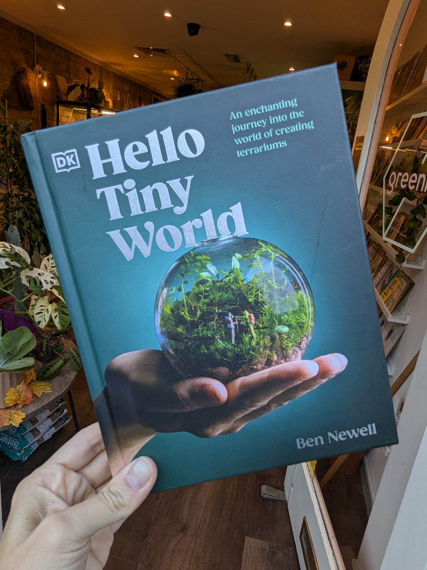 Book titled 'Hello Tiny World' held by a person in a bookstore.