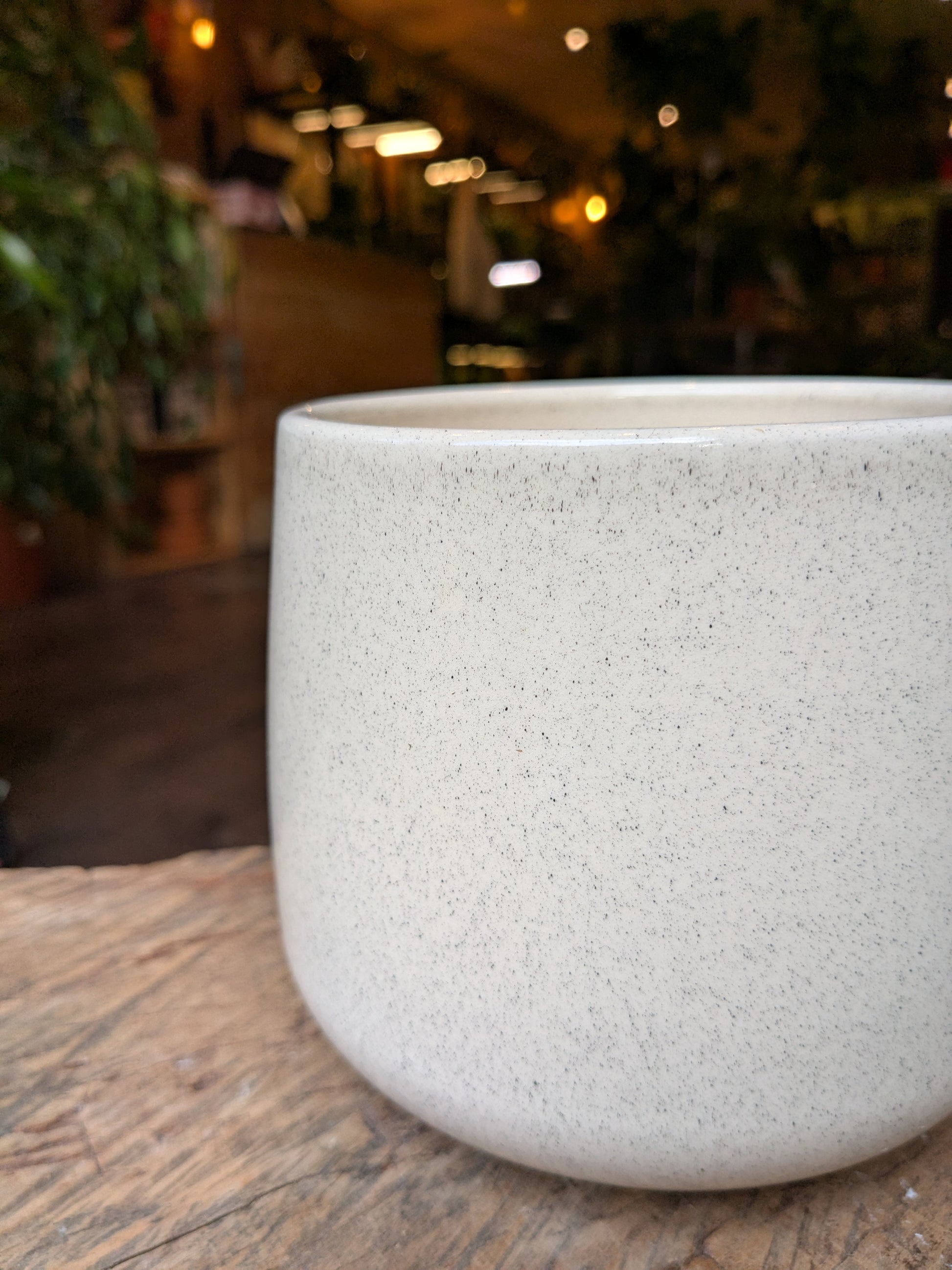 Speckled beige pot on a wooden surface with a blurred indoor background