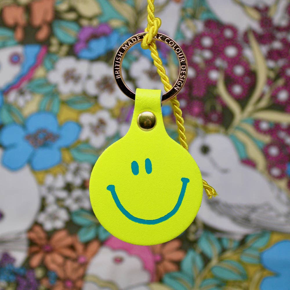 Yellow smiley face keychain with a floral background