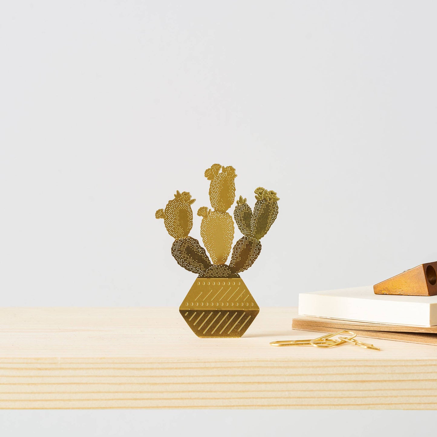 Gold cactus-shaped desk organizer on a light surface with a white background