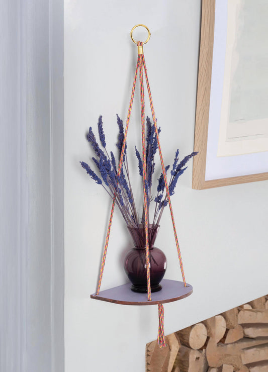 Hanging plant holder with dried lavender against a neutral wall.