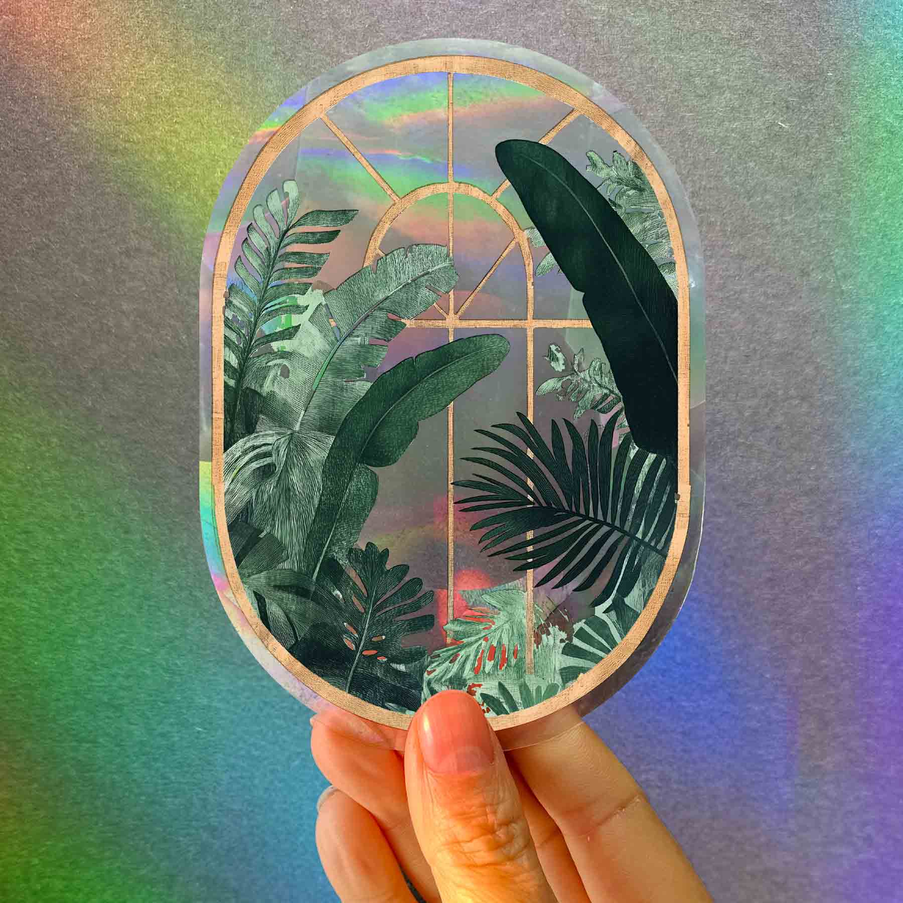 Holographic sticker with tropical leaf design held against a colorful gradient background