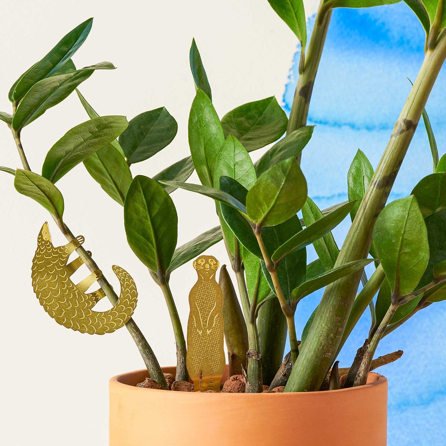 Potted plant with decorative gold lizard figures on a light background