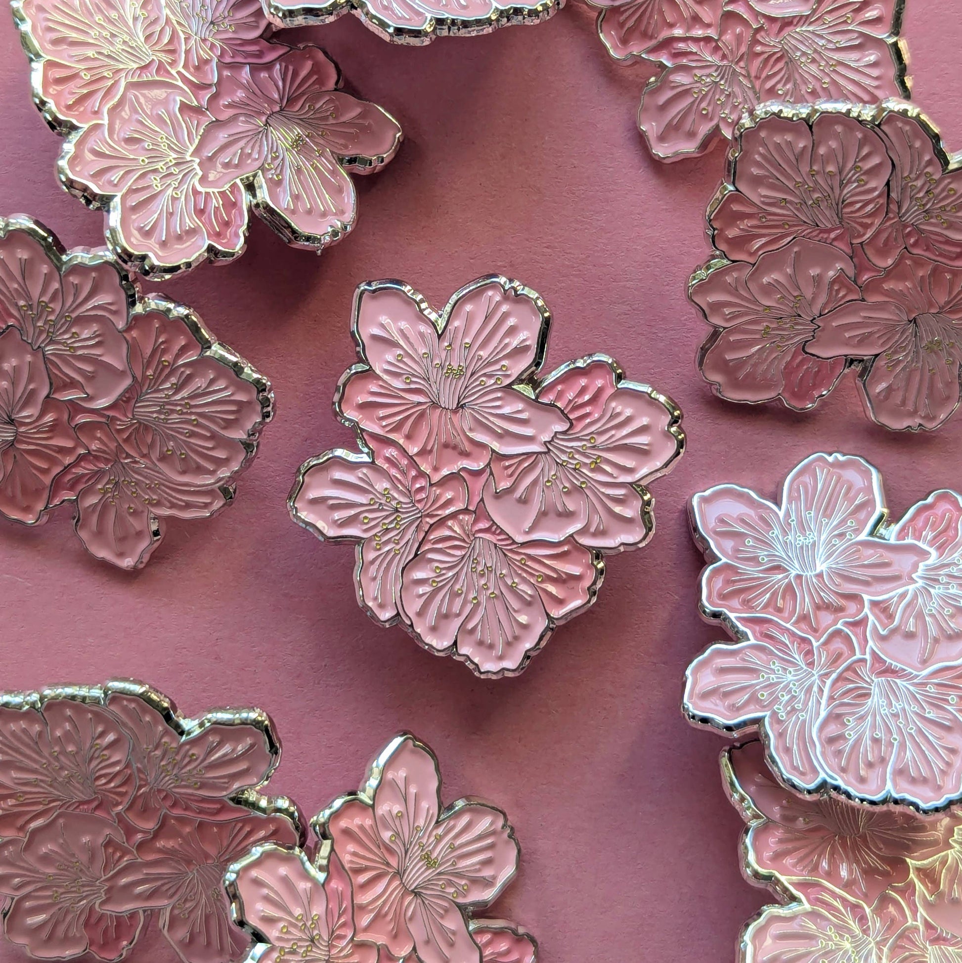 Pink floral pins with gold accents on a pink background