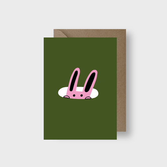 Green greeting card with pink rabbit illustration and brown envelope on a white background