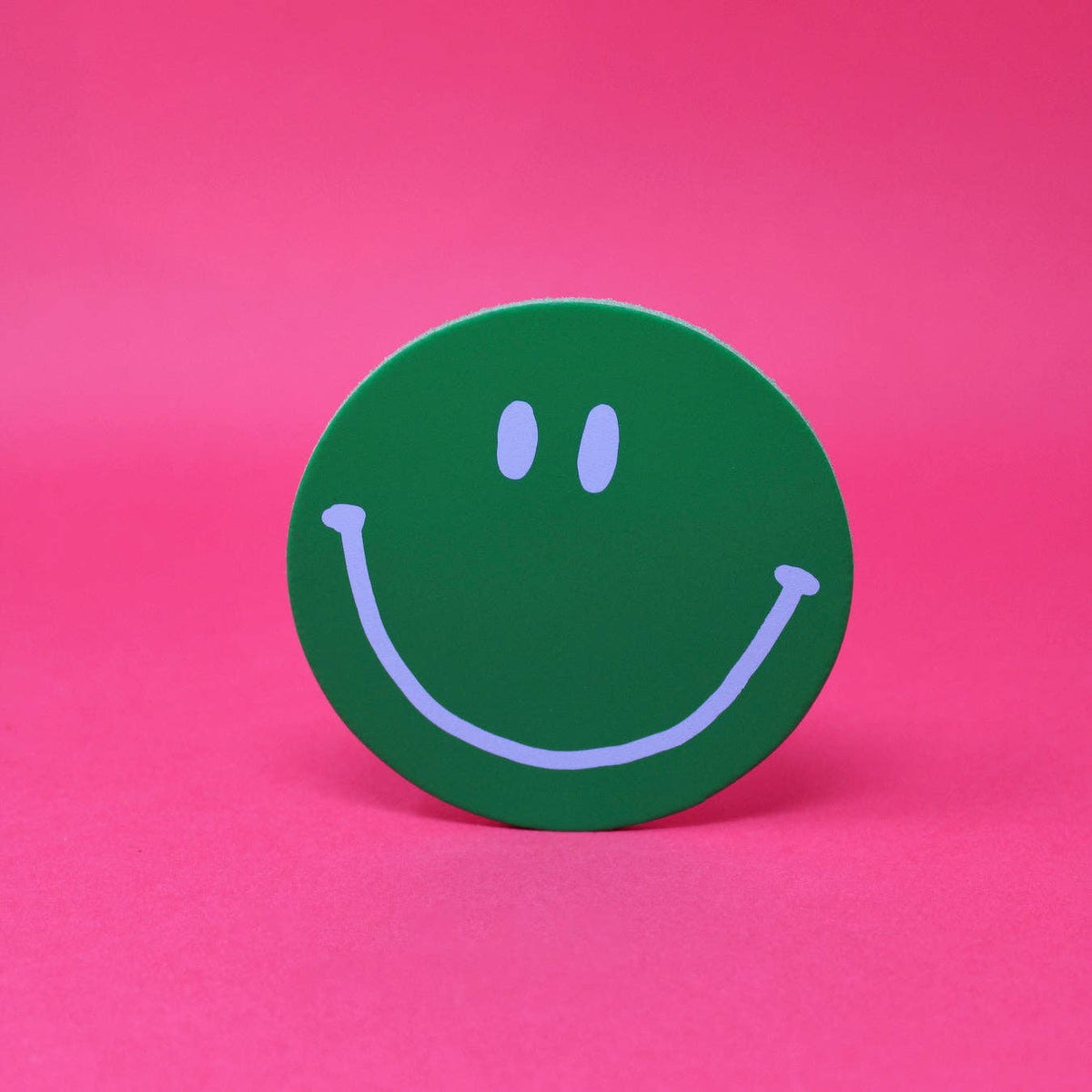 Green smiley face sticker on a pink background