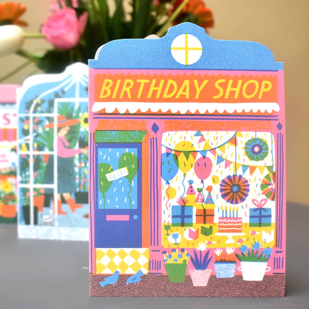 Colorful birthday-themed card with 'Birthday Shop' design on a gray surface.