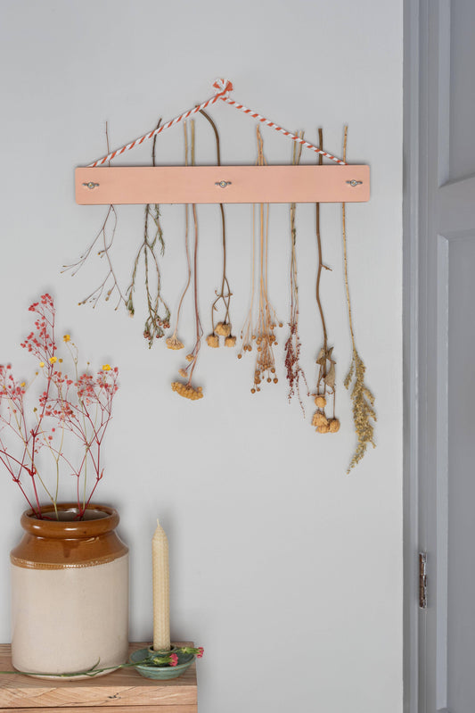 Decorative wall hanging with dried plants on a light gray wall.