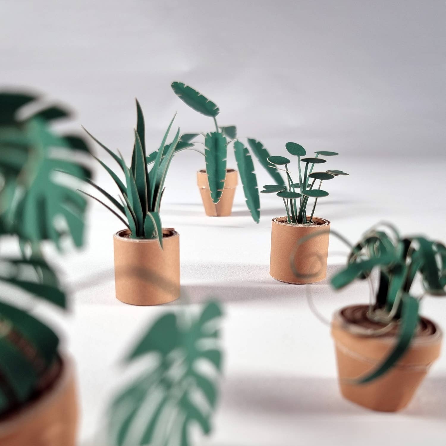 Small potted paper plants on a reflective surface with a neutral background