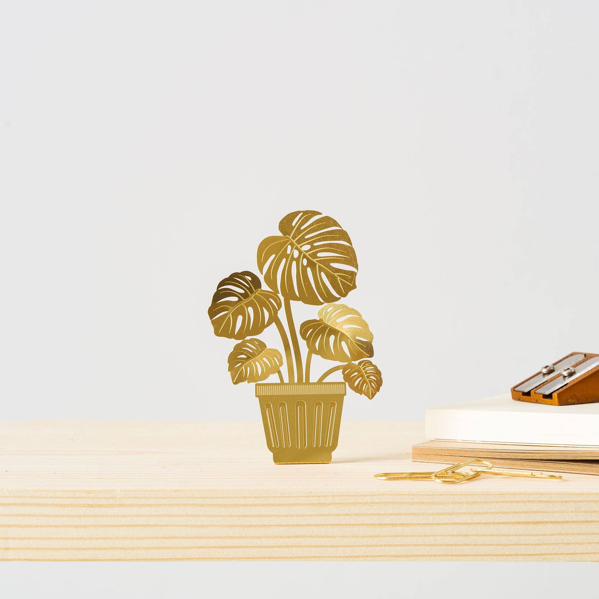 Gold potted plant decal on a white surface with a pen and notebook.