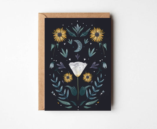 A square greeting card with a kraft envelope, featuring a dark navy background decorated with yellow sunflowers, teal leaves, a gray crescent moon, and a white diamond illustration in the center.