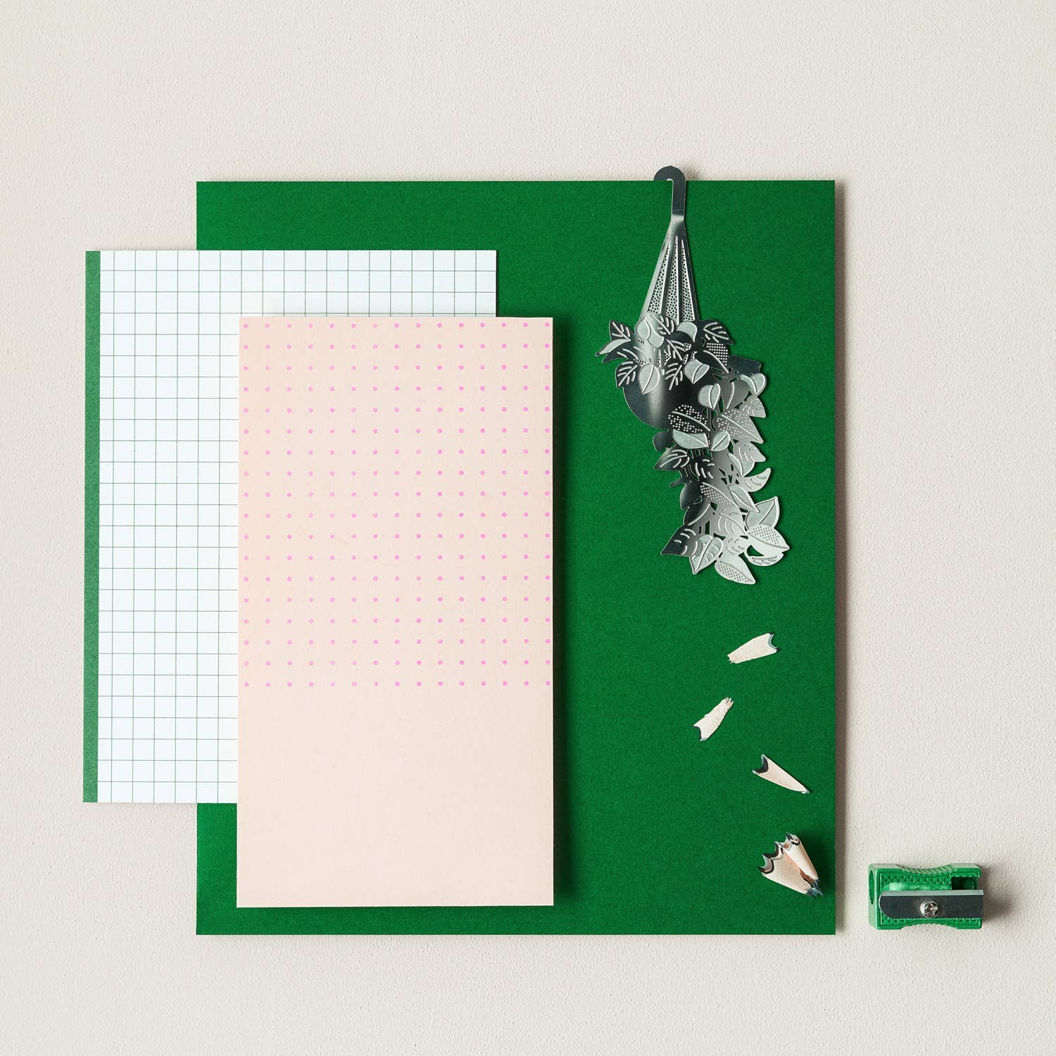 Green notepad with various paper sheets and stationery items on a light background