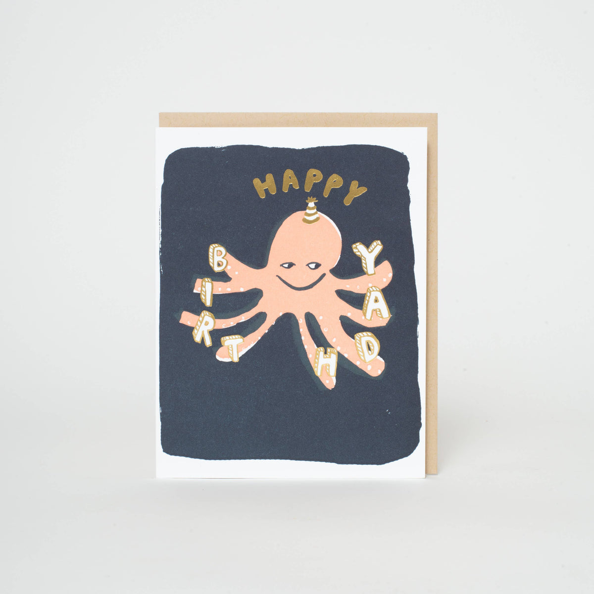 A square birthday card with a dark navy blue background and a peach octopus illustration. The octopus has a small party hat and the word 'HAPPY' is above it, while the letters of 'BIRTHDAY' are arranged along the octopus's tentacles.